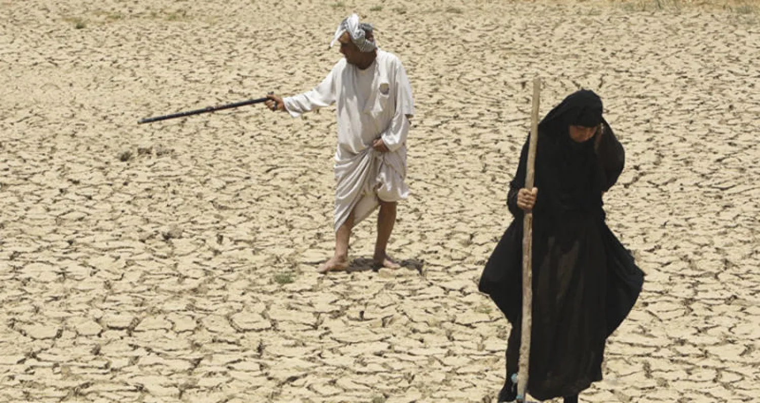 اثنان من سكان الأهوار في جنوب العراق يتجولان في قاع هور بلا ماء جراء الجفاف (أ.ب)