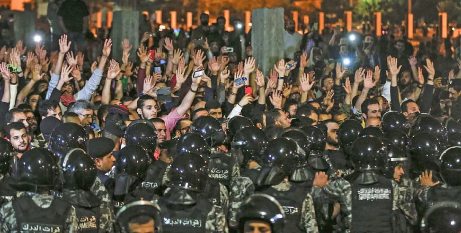 Protesters raise their hands before members of the Gendarmerie and security forces during a demonstration outside the prime minister's office in Amman early Sunday (AFP photo by Khalil Mazraawi)