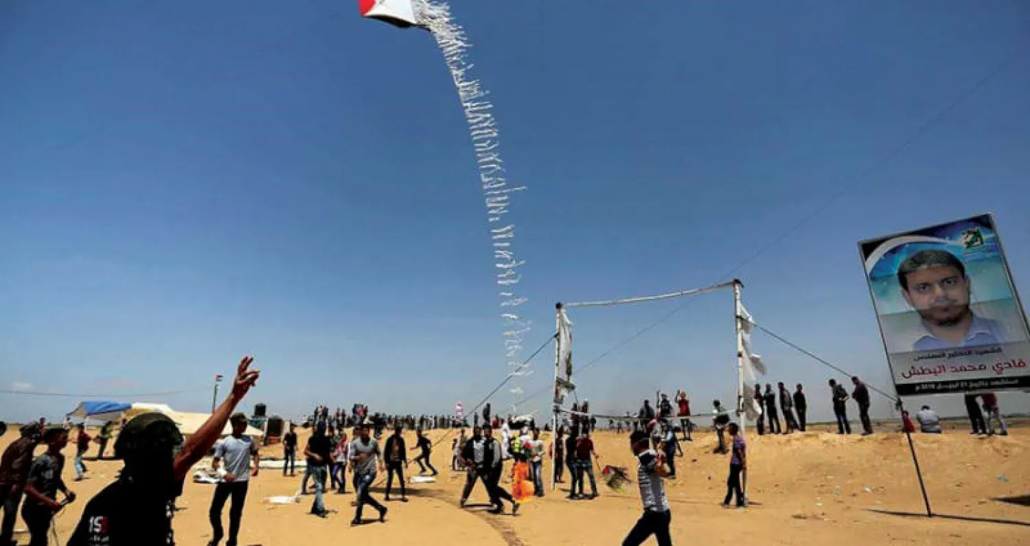 شبان يلعبون كرة القدم وآخرون يطلقون طائرة ورقية بألوان العلم الفلسطيني