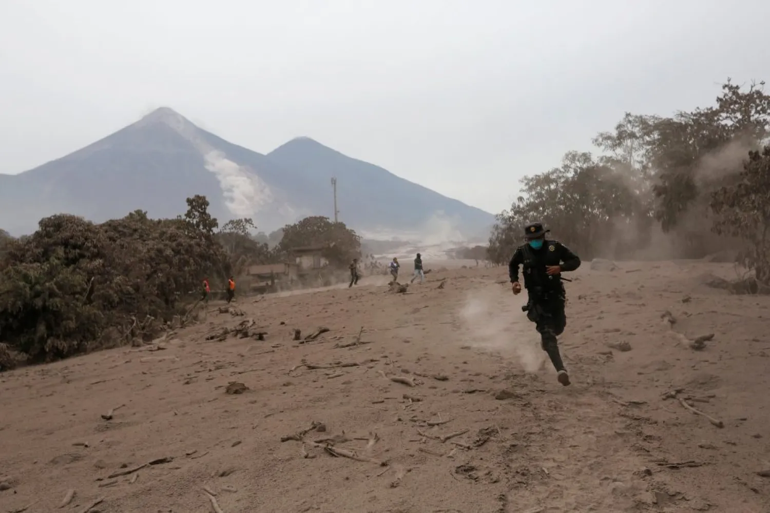 A police officer runs away after the Fuego volcano spew new pyroclastic flow in the community of San Miguel Los Lotes in Escuintla, Guatemala, Monday. (Reuters)
