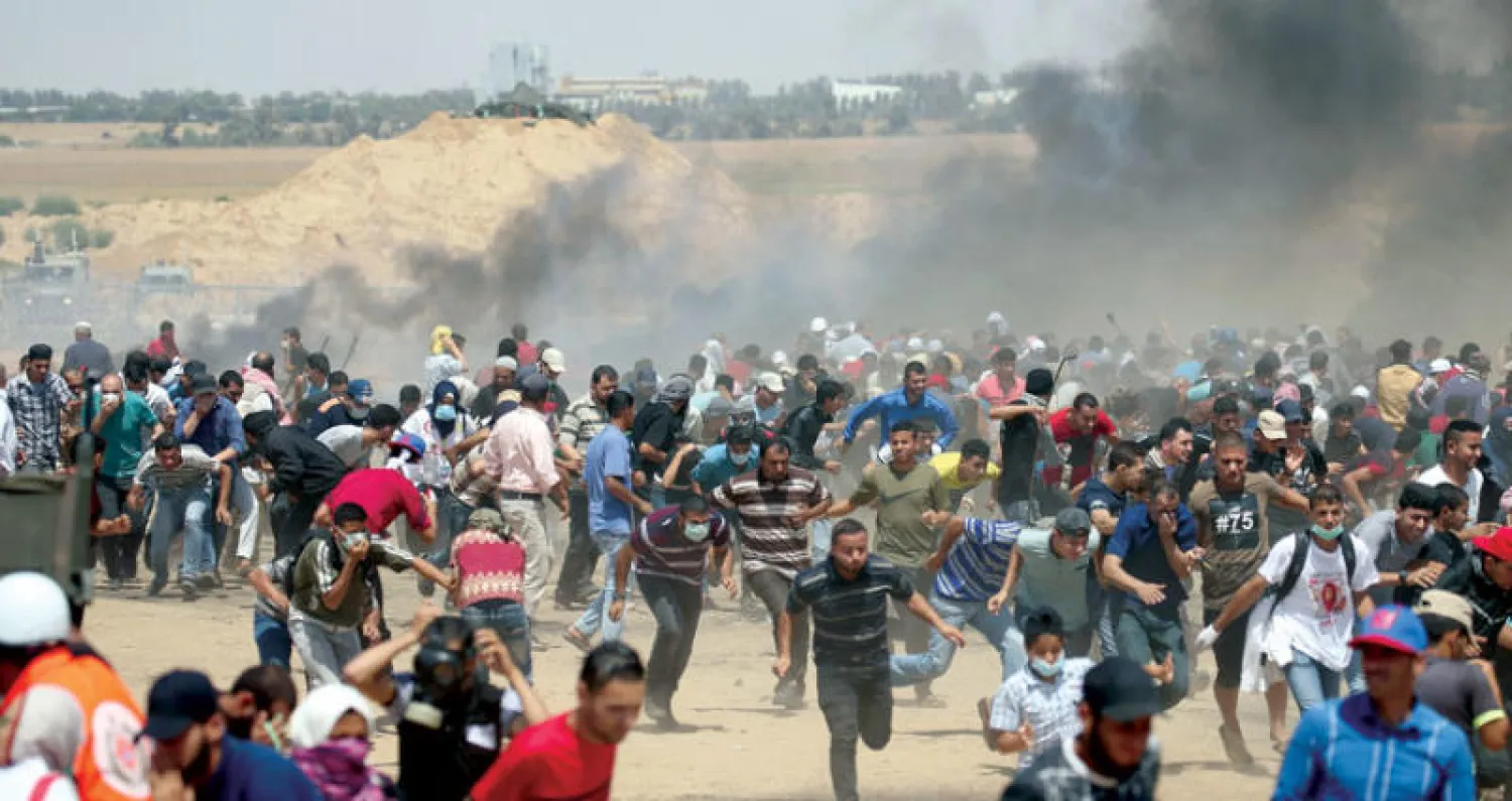 فلسطينيون بعد تعرضهم لإطلاق النار وقنابل الغاز المسيل للدموع خلال المسيرات الاحتجاجية في جنوب قطاع غزة أمس (رويترز)