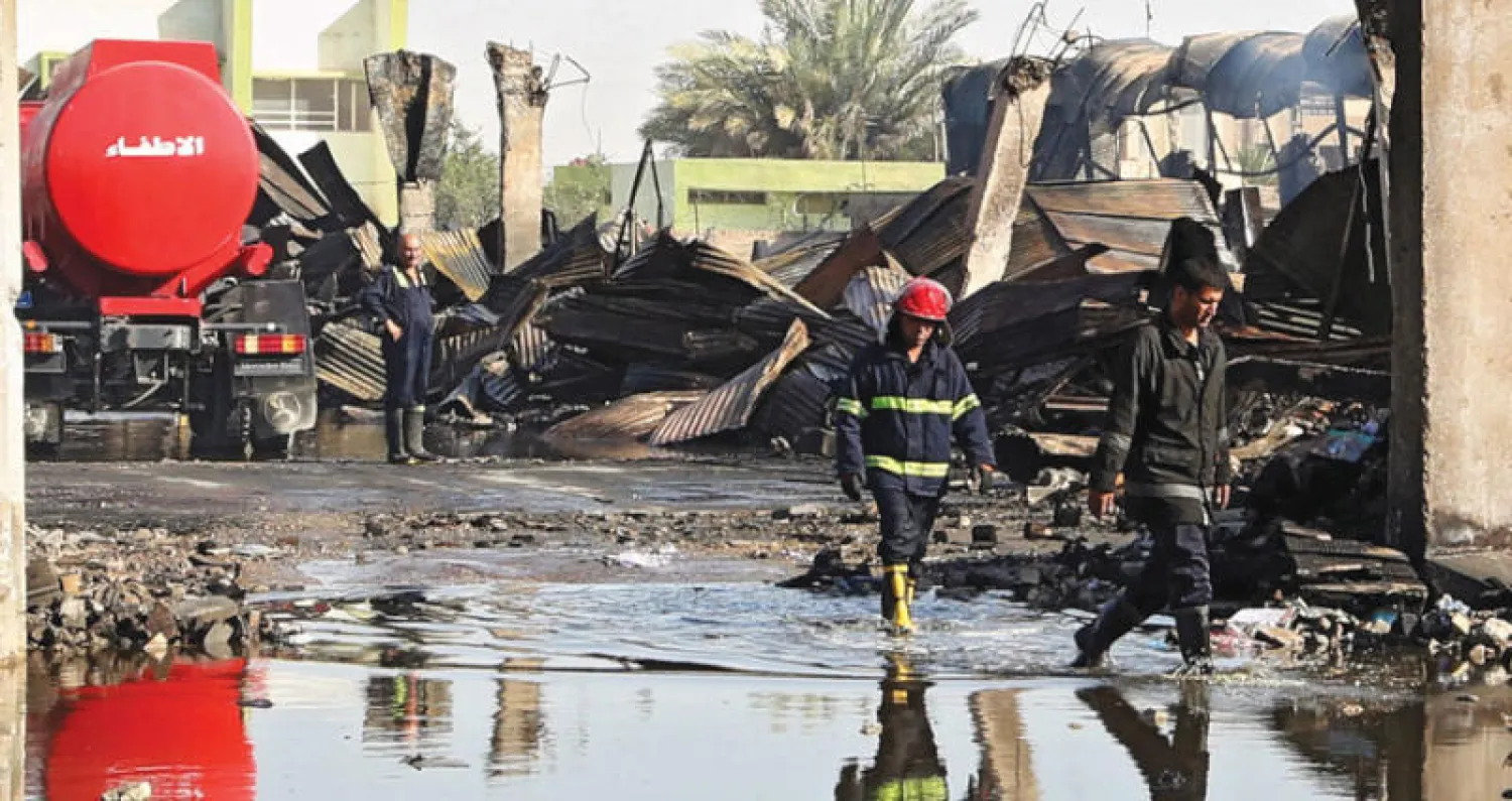 إطفائيان يفحصان موقع الحريق في أحد مخازن صناديق الاقتراع ببغداد أمس (إ.ب.أ)