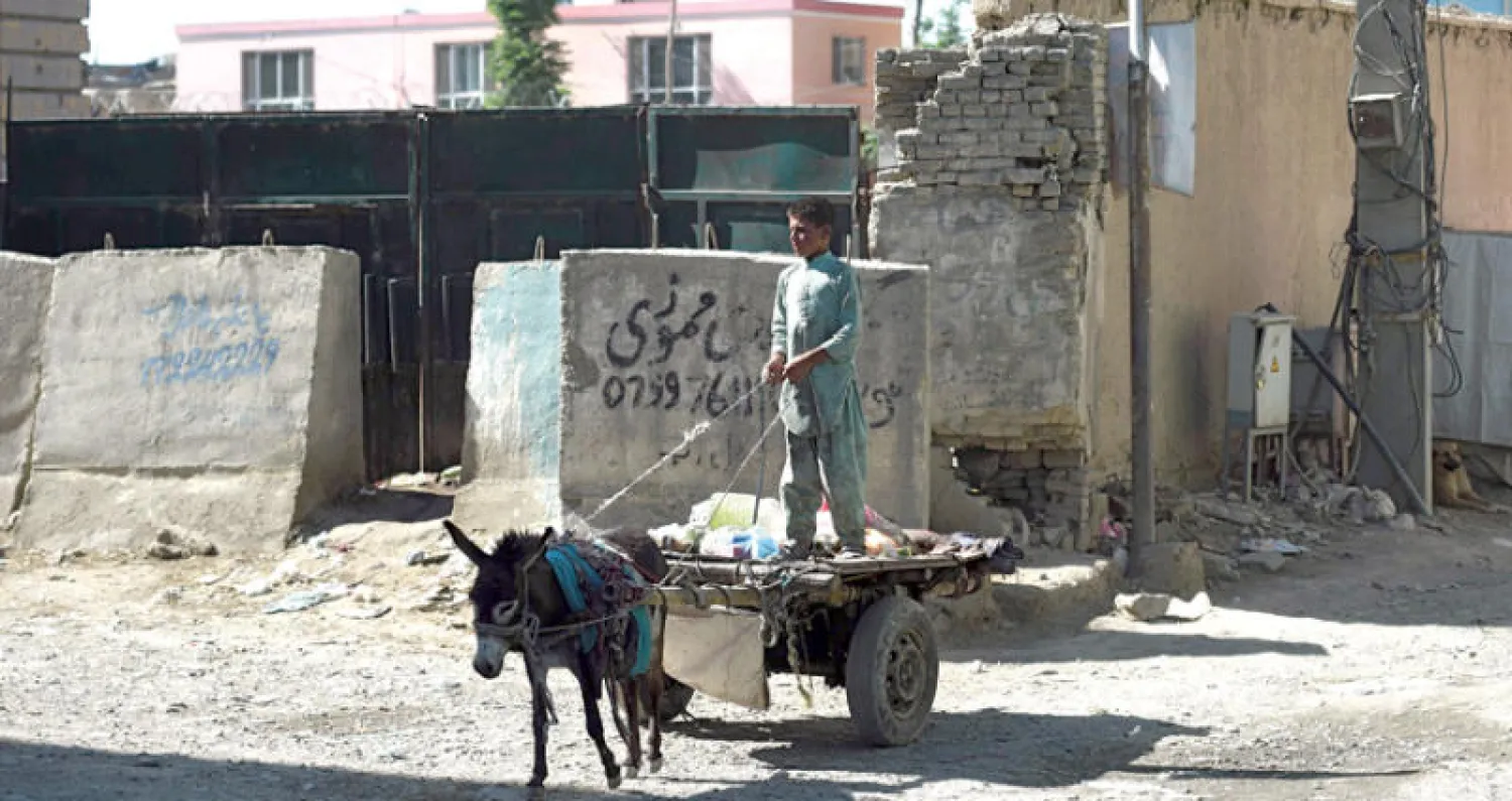 صبي أفغاني ينقل قمامة على عربة يجرها حمار في أحد شوارع العاصمة كابل أمس (أ.ف.ب)