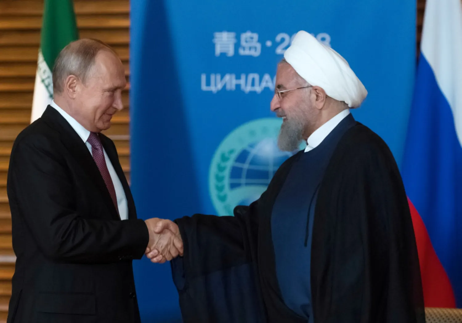 Russian President Vladimir Putin (L) shakes hands with Iranian President Hassan Rouhani during a meeting on the sidelines of the Shanghai Cooperation Organisation Summit (SCO) in Qingdao, China June 9, 2018. Sputnik/Sergei Guneev/Kremlin via REUTERS
