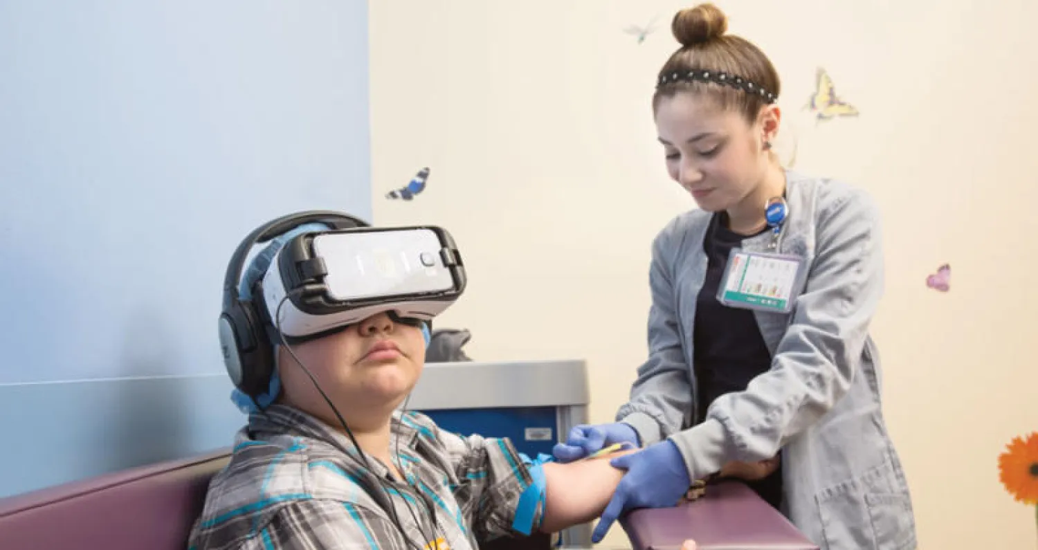 طفل يرتدي جهاز الواقع الافتراضي لتشتيت انتباهه بينما تحقنه ممرضة ({واشنطن بوست})