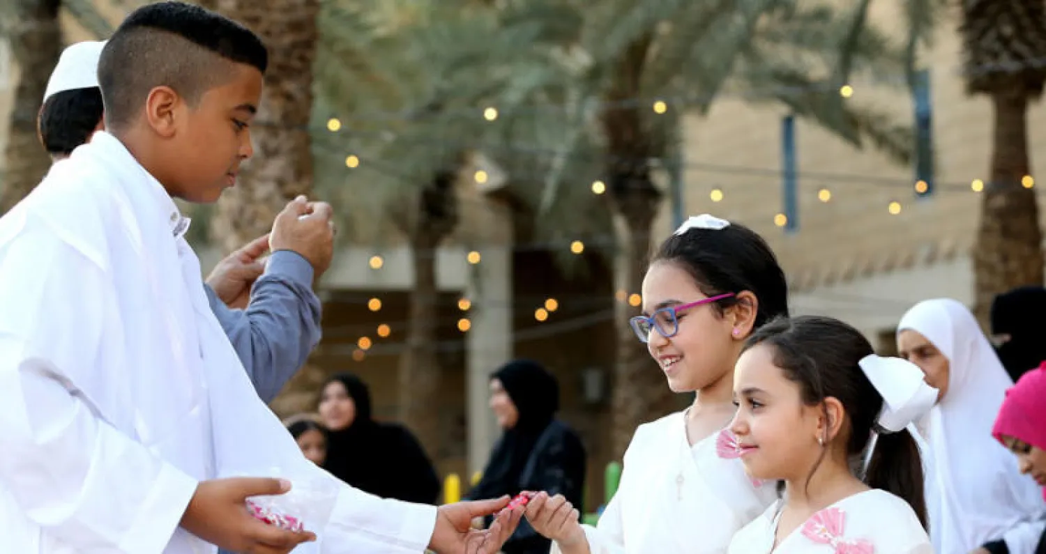 صبي يقدم الحلوى للأطفال بعد صلاة العيد بمسجد في العاصمة السعودية الرياض (إ.ب.أ)