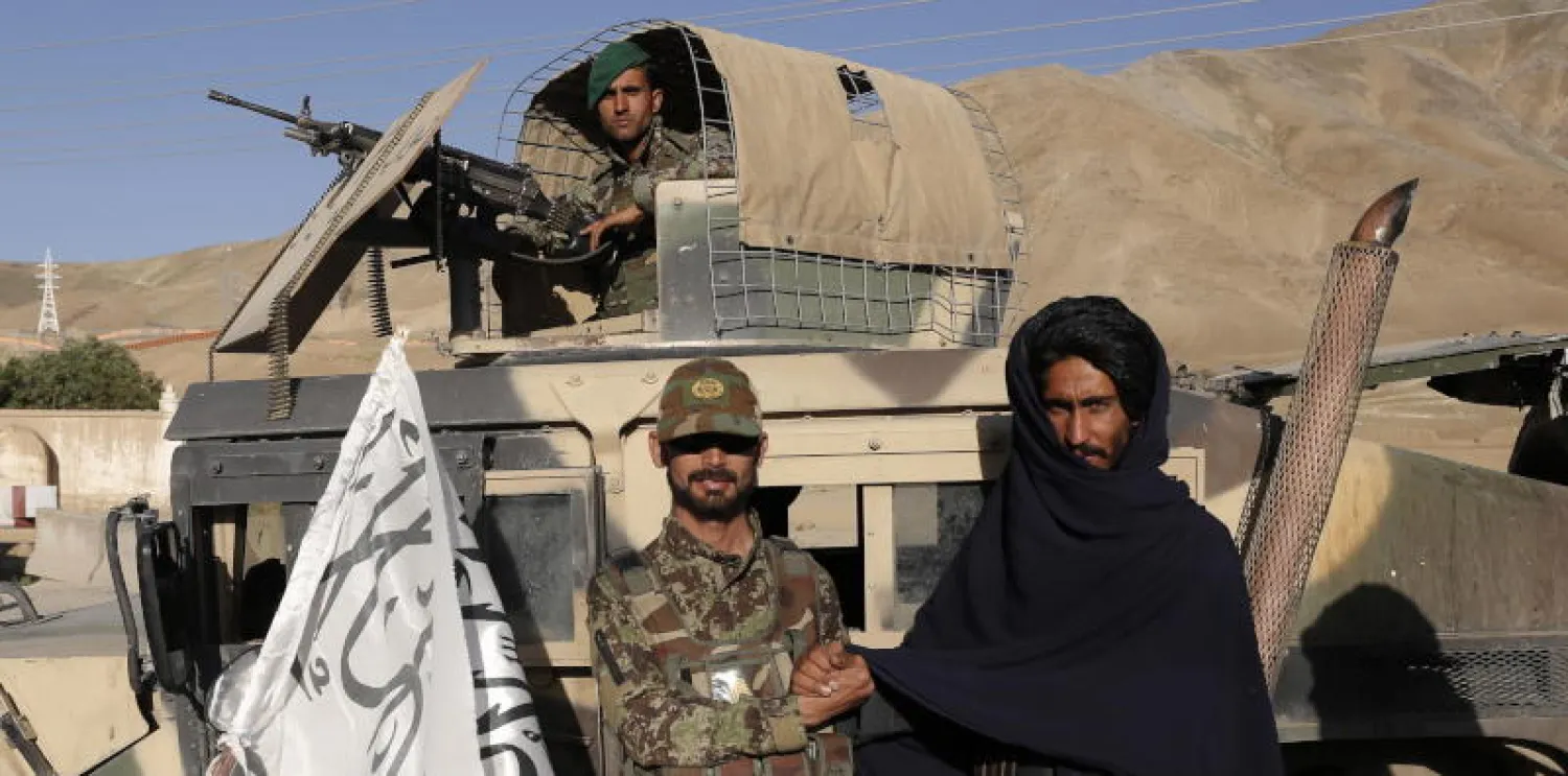 مقاتل من طالبان يصافح جندياً أفغانياً في إطار هدنة عيد الفطر (إ.ب.أ)