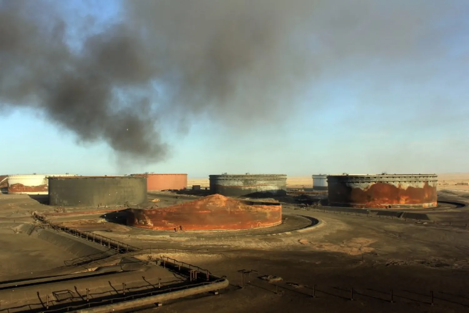 A file photo taken on January 08, 2016 shows smoke billowing from a petroleum storage tank after a fire was extinguished at Al-Sidra oil terminal, near Ras Lanuf in the so-called "oil crescent" along Libya's northern coast. STRINGER / AFP