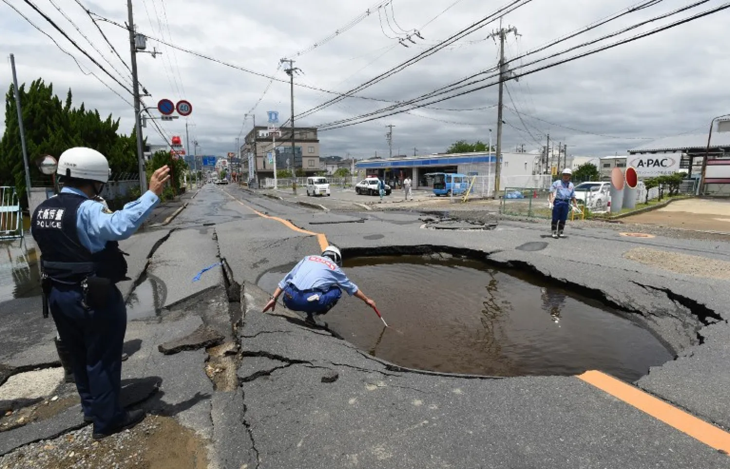 Police check a collapsed road following an earthquake in Takatsuki, north of Osaka prefecture on June 18, 2018. STR / JIJI PRESS / AFP