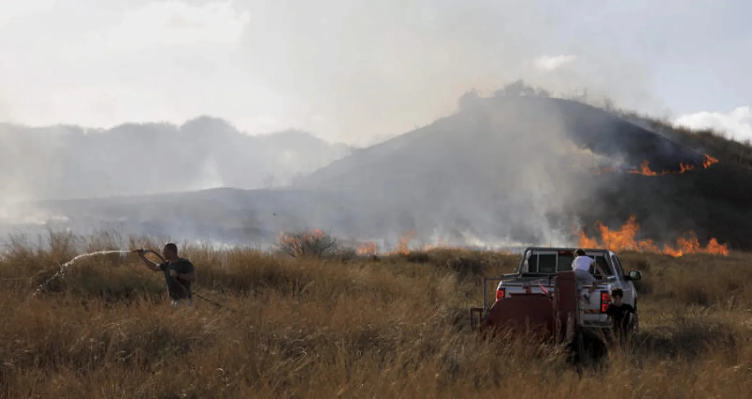 إسرائيلي يحاول إطفاء نيران في حقول تابعة لكيبوتس بئيري في محيط غزة (أ.ف.ب)