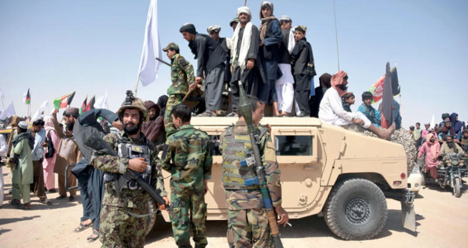 عناصر من «طالبان» على سيارة «همفي» إلى جانب جنود أفغان خلال الاحتفالات بثالث أيام عيد الفطر في مديرية مياوند بولاية قندهار جنوب البلاد (أ.ف.ب)