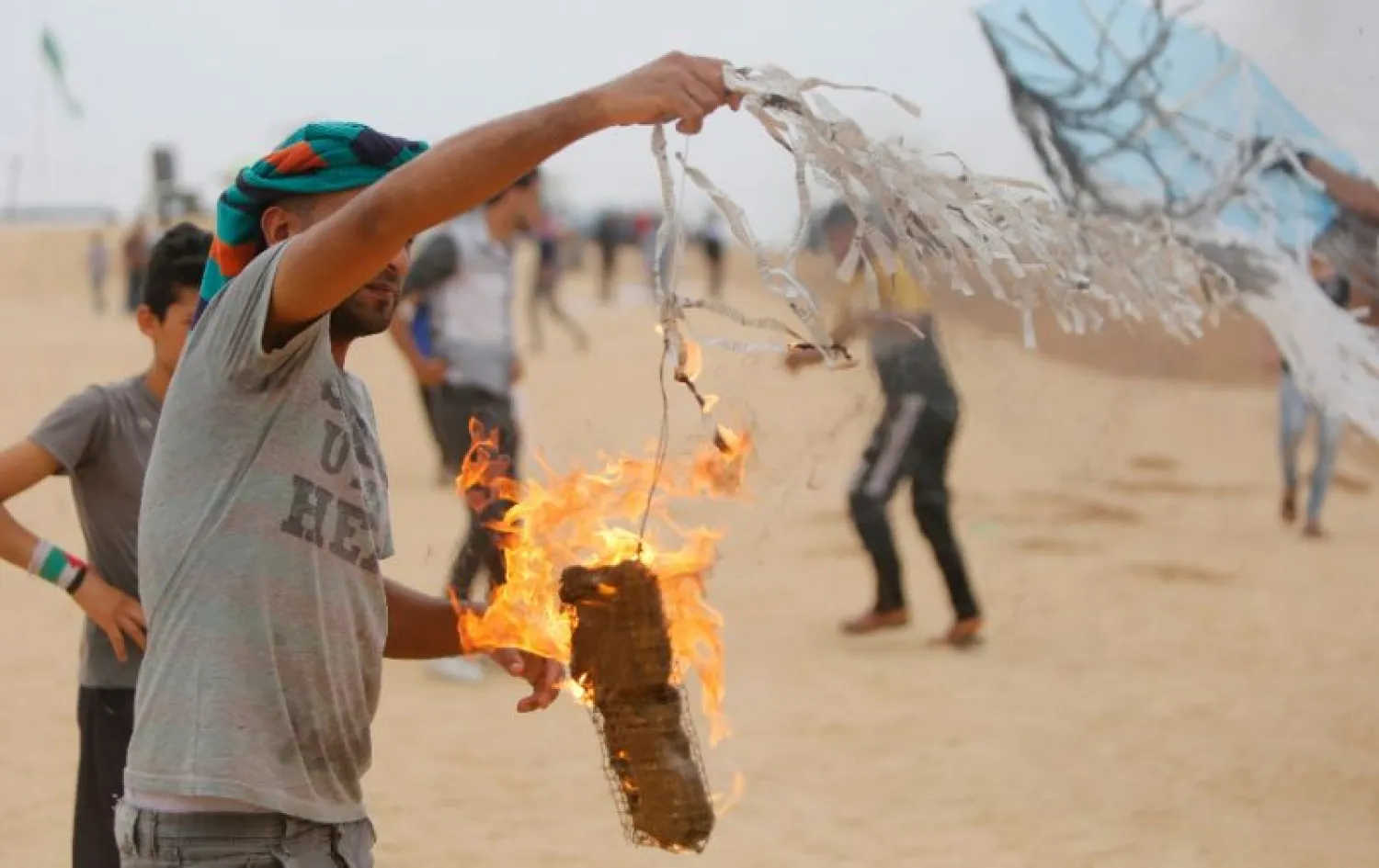 A Palestinians protester attaches an incendiary device to a kite before trying to fly it over the border fence between Gaza and Israel on May 4, 2018. (AFP)