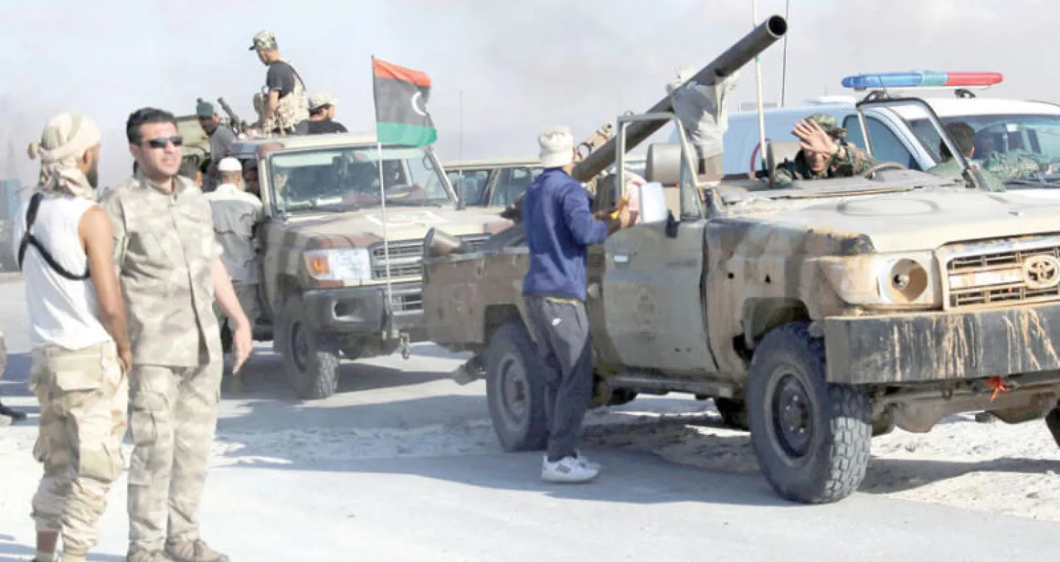 عناصر من الجيش الليبي يرفعون العلم الليبي فوق سيارتهم بعد استعادة السيطرة على ميناء راس لانوف (رويترز)