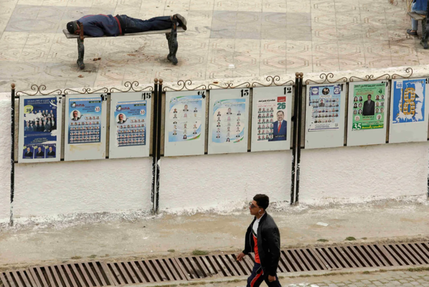 A man walks past campaign election posters in Algiers (Reuters)

