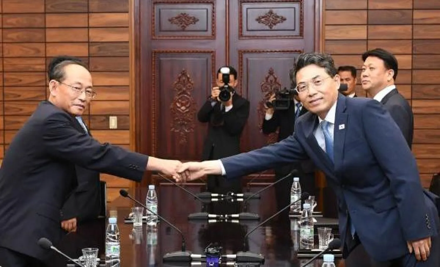 نائب وزير النقل الكوري الجنوبي كيم جيونغ ريول يصافح نظيره الكوري الشمالي باك هو يونغ خلال لقائهما عند الحدود (أ.ف.ب)