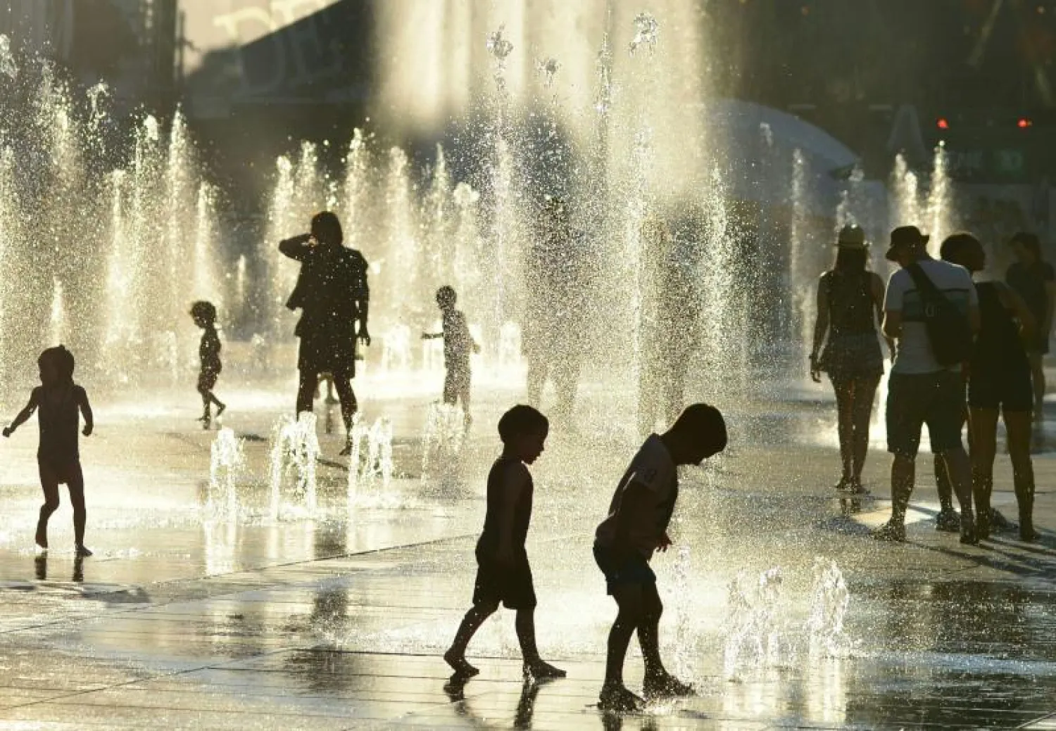 أطفال يلعبون في نافورة مياه بمونتريال هرباً من الحرارة المرتفعة (أ.ف.ب)