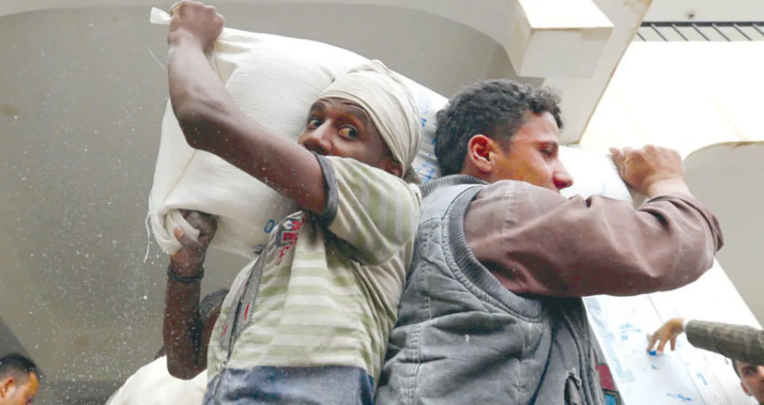 يمنيان يحملان مساعدات قدمها برنامج الغذاء العالمي في صنعاء أمس (إ.ب.أ)