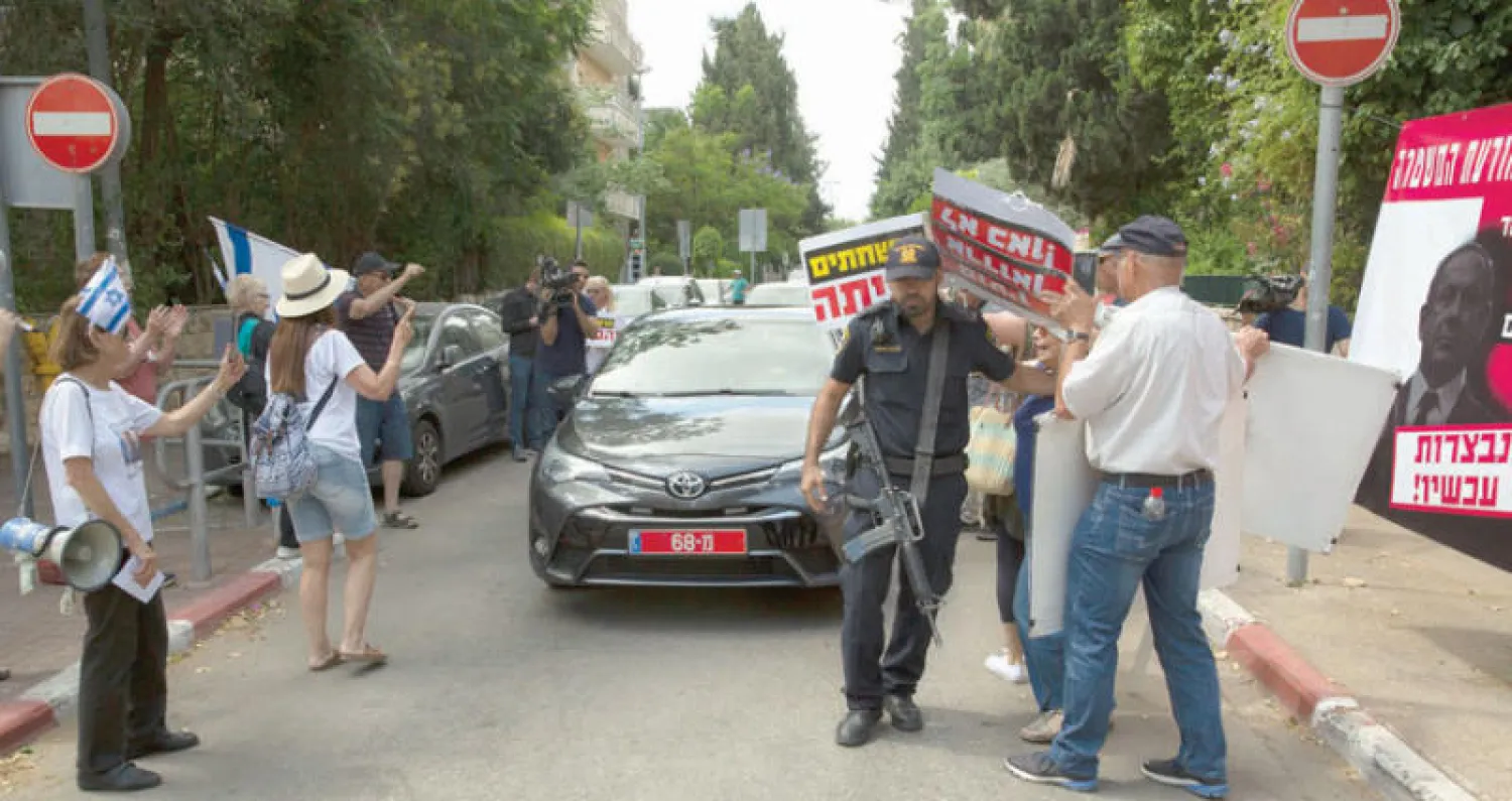 عناصر من الشرطة الإسرائيلية تبعد متظاهرين أمام منزل نتنياهو لدى وصول محققين لاستجوابه في فضائح فساد أواسط الشهر الماضي (أ. ب)