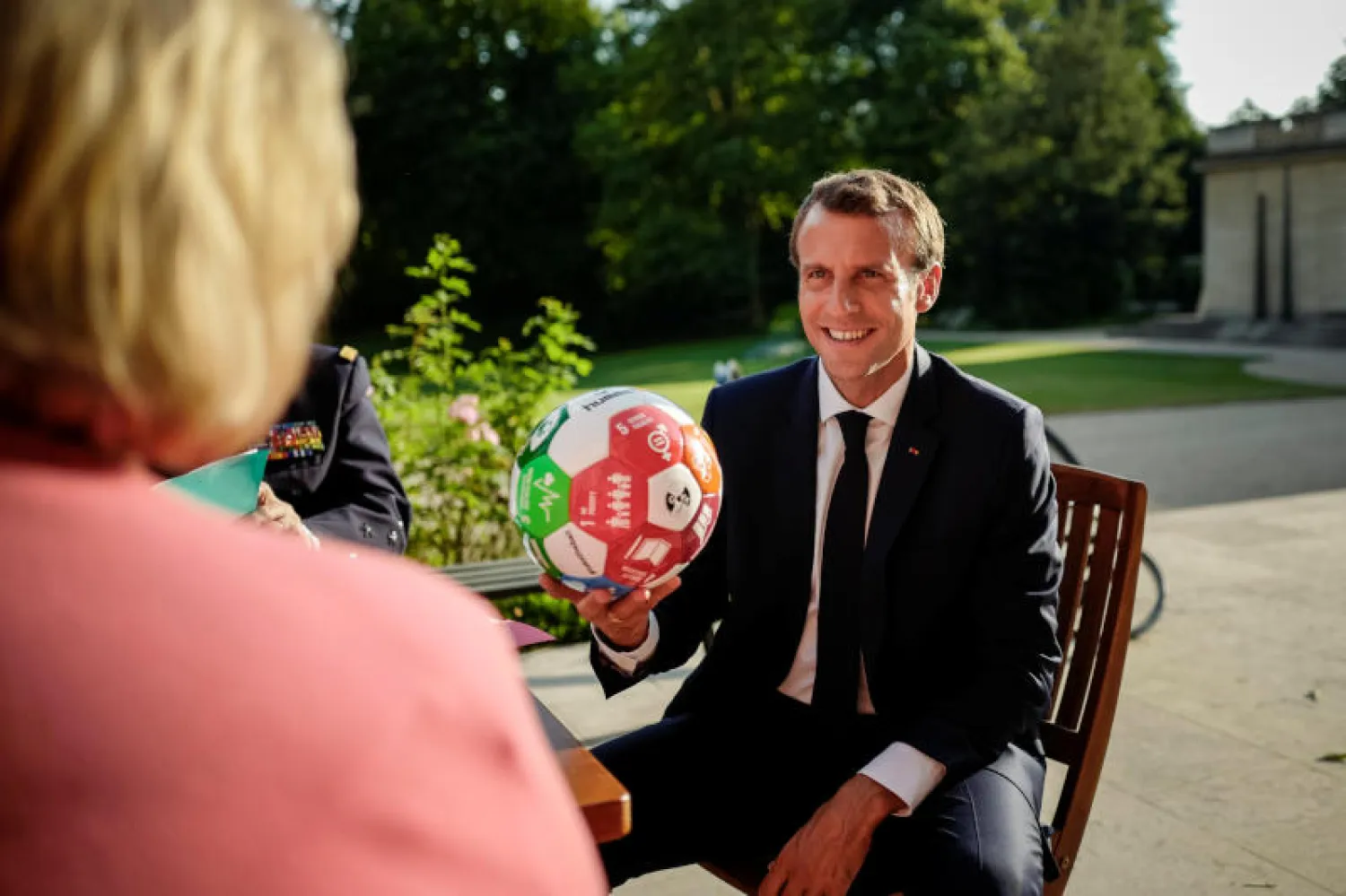 الرئيس الفرنسي إيمانويل ماكرون يحمل كرة مقدّمة من رئيسة وزراء النرويج إرنا سولبرغ في الإليزيه (رويترز)