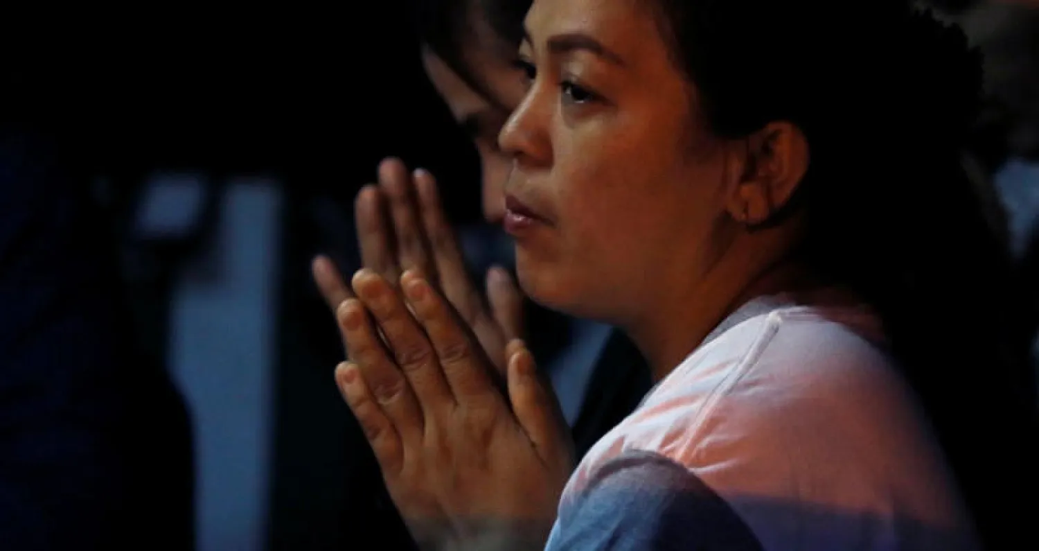 امرأة من أقارب الأطفال المحتجزين تصلي بالقرب من الكهف (رويترز)