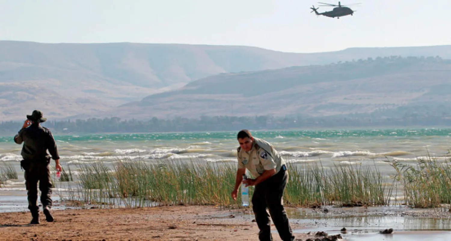 عنصران من القوات الإسرائيلية يبحثان عن بقايا درون جاءت من سوريا وسقطت في ساحل الجليل (أ.ف.ب)