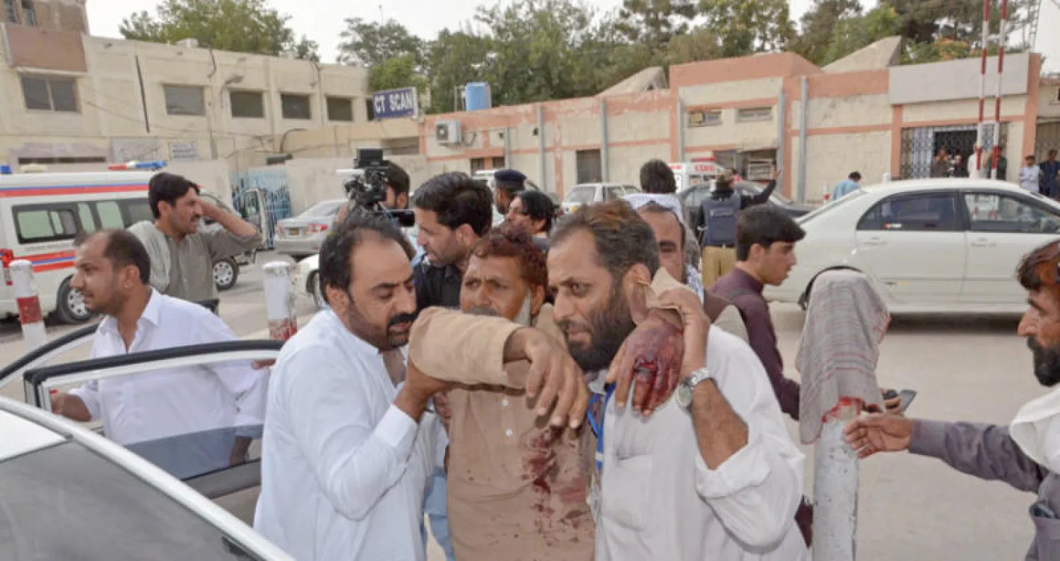باكستانيون يجلون جريحاً في الهجوم الانتحاري بولاية بلوشستان أمس (إ.ب.أ)