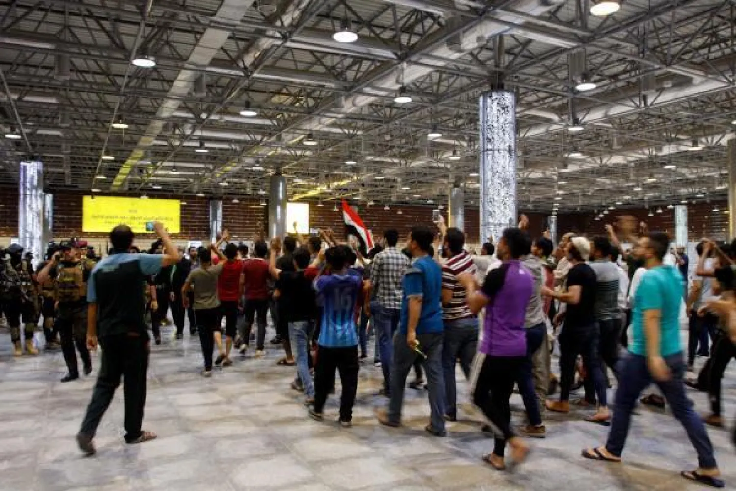 متظاهرون خلال اقتحامهم مطار النجف الدولي بالعراق مساء أمس (ا.ف.ب)