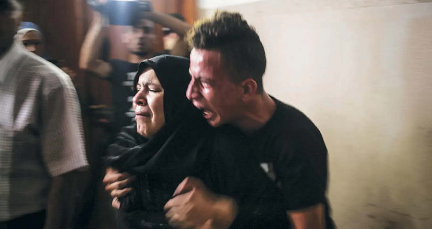 والدة وشقيق طفل فلسطيني قتل بهجوم إسرائيلي يبكيانه أثناء تشييعه في غزة أمس (إ.ب.أ)