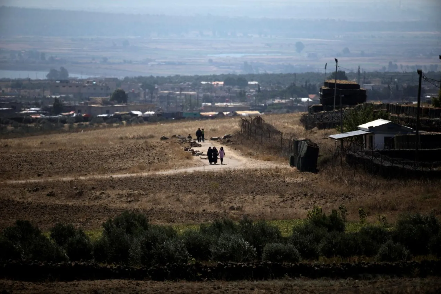People walk near the Israel-Syria border line as it is seen from the Israeli-occupied Golan Heights, Israel. (Reuters)