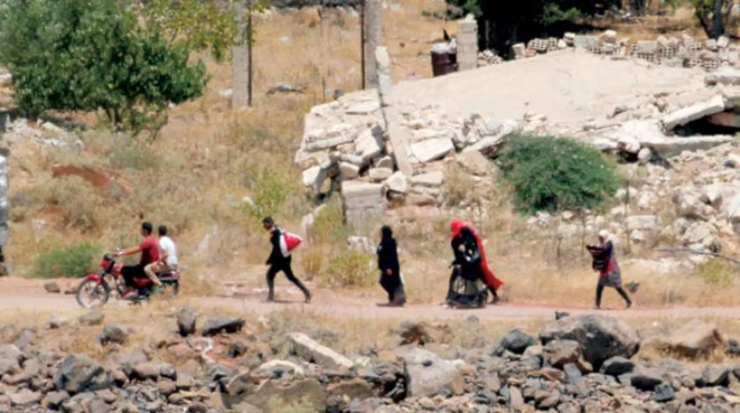 A picture taken on July 20, 2018 from the Israeli-annexed Golan Heights shows Syrians walk with their belongings as they prepare to leave the village of Qahtaniyah, near the border in southwestern Syria. JALAA MAREY / AFP