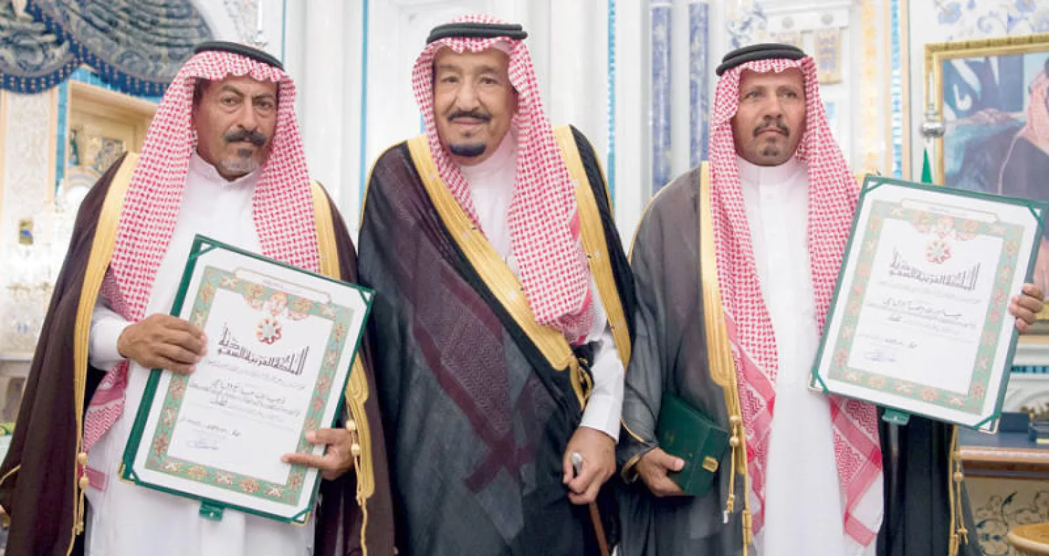 خادم الحرمين متوسطاً ذوي الطالبين في صورة تذكارية بعد تسلمهما «وسام الملك عبد العزيز» (واس)