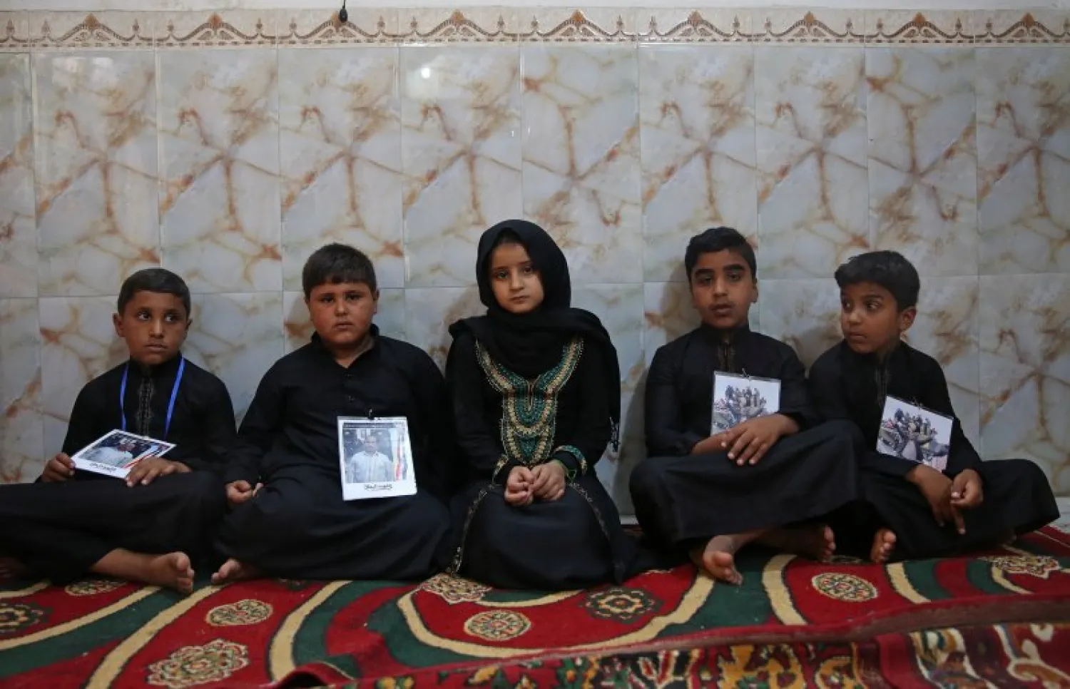 Children hold pictures of their fathers, who were killed by ISIS militants at Kirkuk road, Iraq July 5, 2018. REUTERS/Abdullah Dhiaa al-Deen