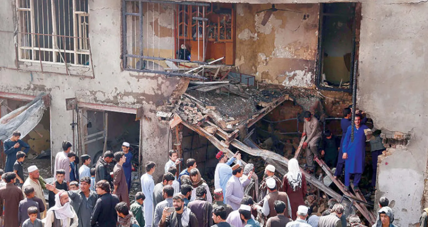 أفغان يعاينون اضرار التفجير الانتحاري في مقر الاستخبارات في كابل أمس (إ.ب.أ)