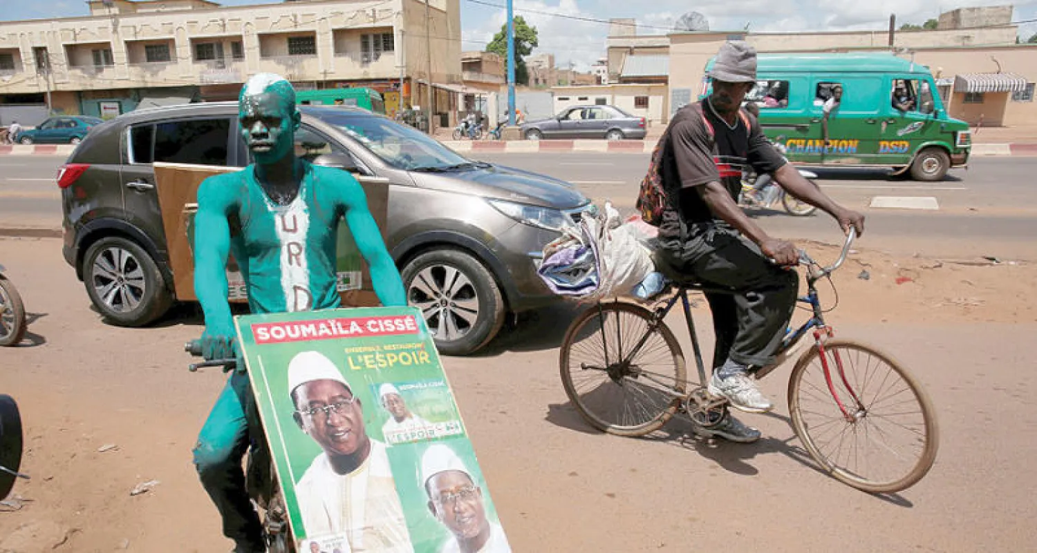 أحد المؤيدين يحمل ملصقاً في باماكو لزعيم المعارضة صومايلا سيسي (رويترز)