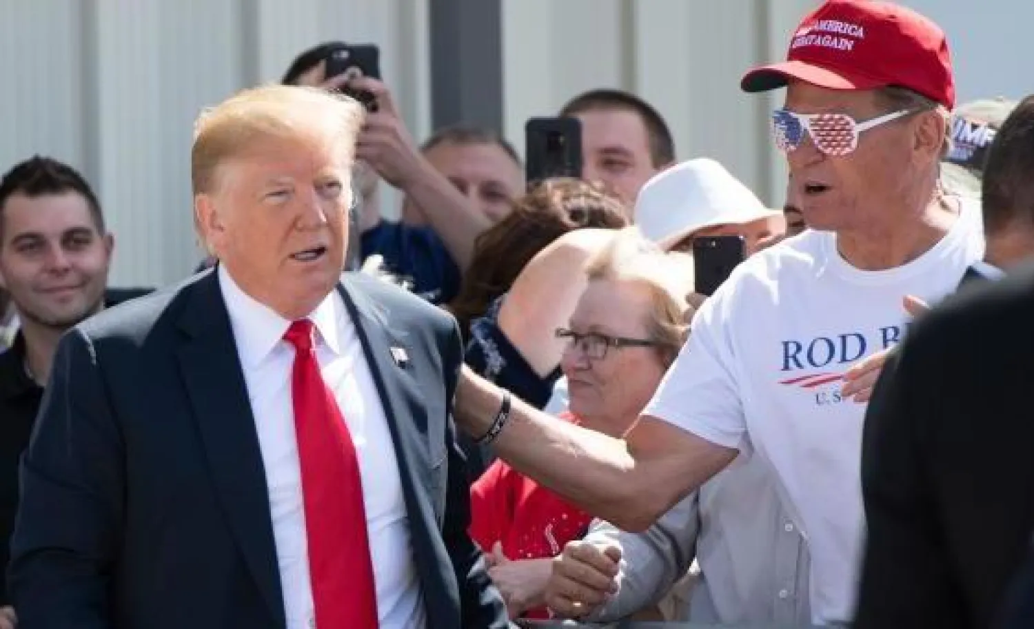 الرئيس الأميركي دونالد ترمب يحيي أنصاره بعد وصوله إلى مطار دوبوك الإقليمي (أ.ف.ب)