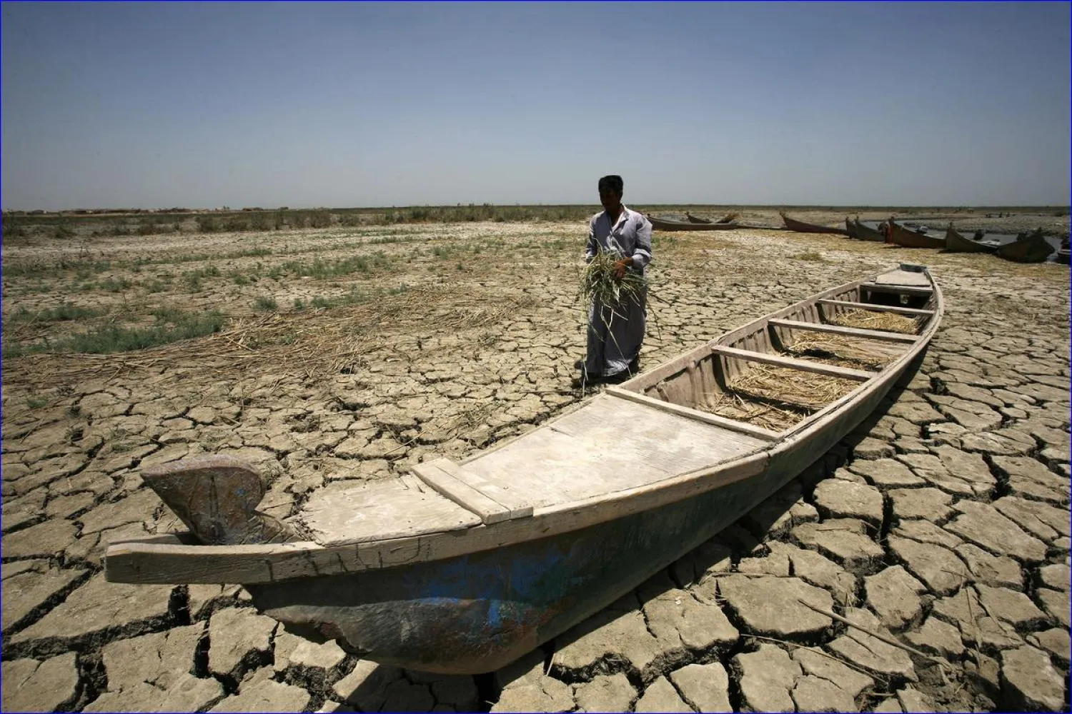 An Iraqi man walks past a canoe siting on dry earth in the Chibayish marshes near Nasiriyah, Iraq. (AFP)