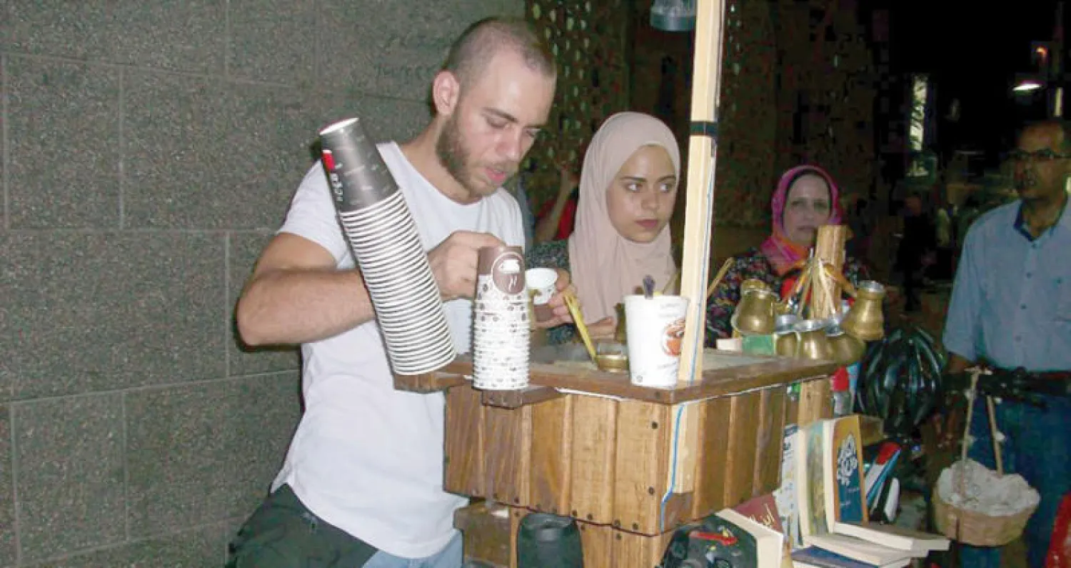 الشاب بندق أمام عربته يعد القهوة ويجذب زبائنه بالكتب ({الشرق الأوسط})