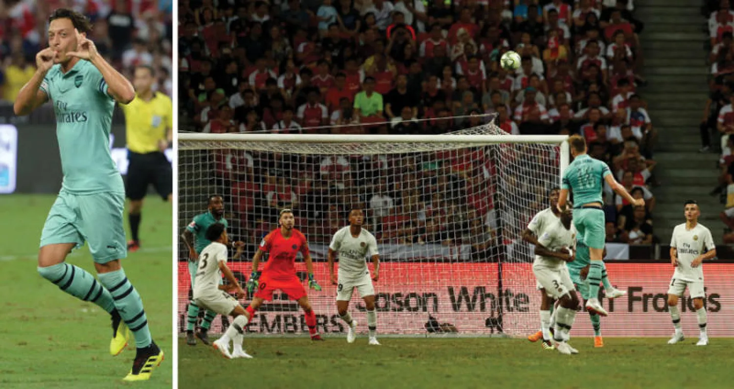 هولدينغ لاعب آرسنال يقفز عالياً ليسجل برأسه في مرمى سان جيرمان (رويترز)  -  أوزيل يحتفل بهدفه الافتتاحي لفريق آرسنال (أ.ف.ب)