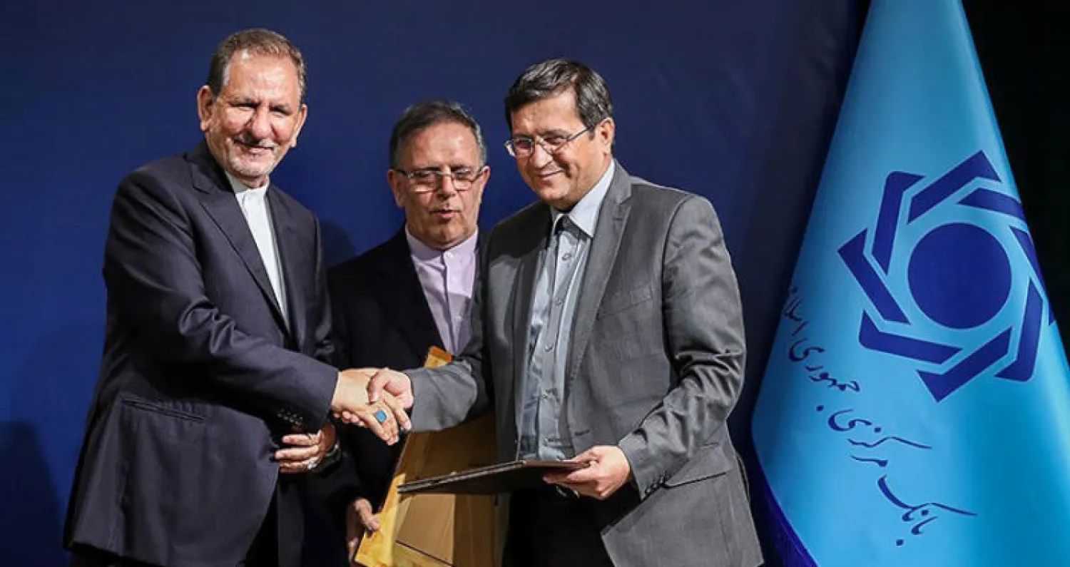 نائب الرئيس الإيراني إسحاق جهانغيري يسلّم رئيس البنك المركزي الجديد عبد الناصر همتي مرسوم تعيينه ويتوسطهما الرئيس السابق ولي الله سيف في طهران أمس (تسنيم)