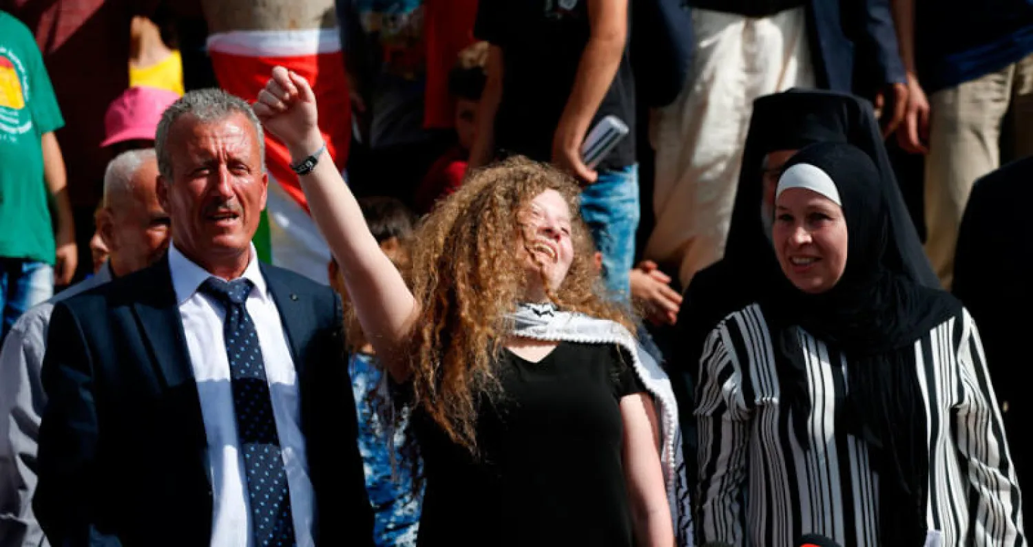 عهد خلال حديثها لوسائل الإعلام وقد بدت فرحة تلوح بسعادة وهي تقف بين والديها (أ.ف.ب)