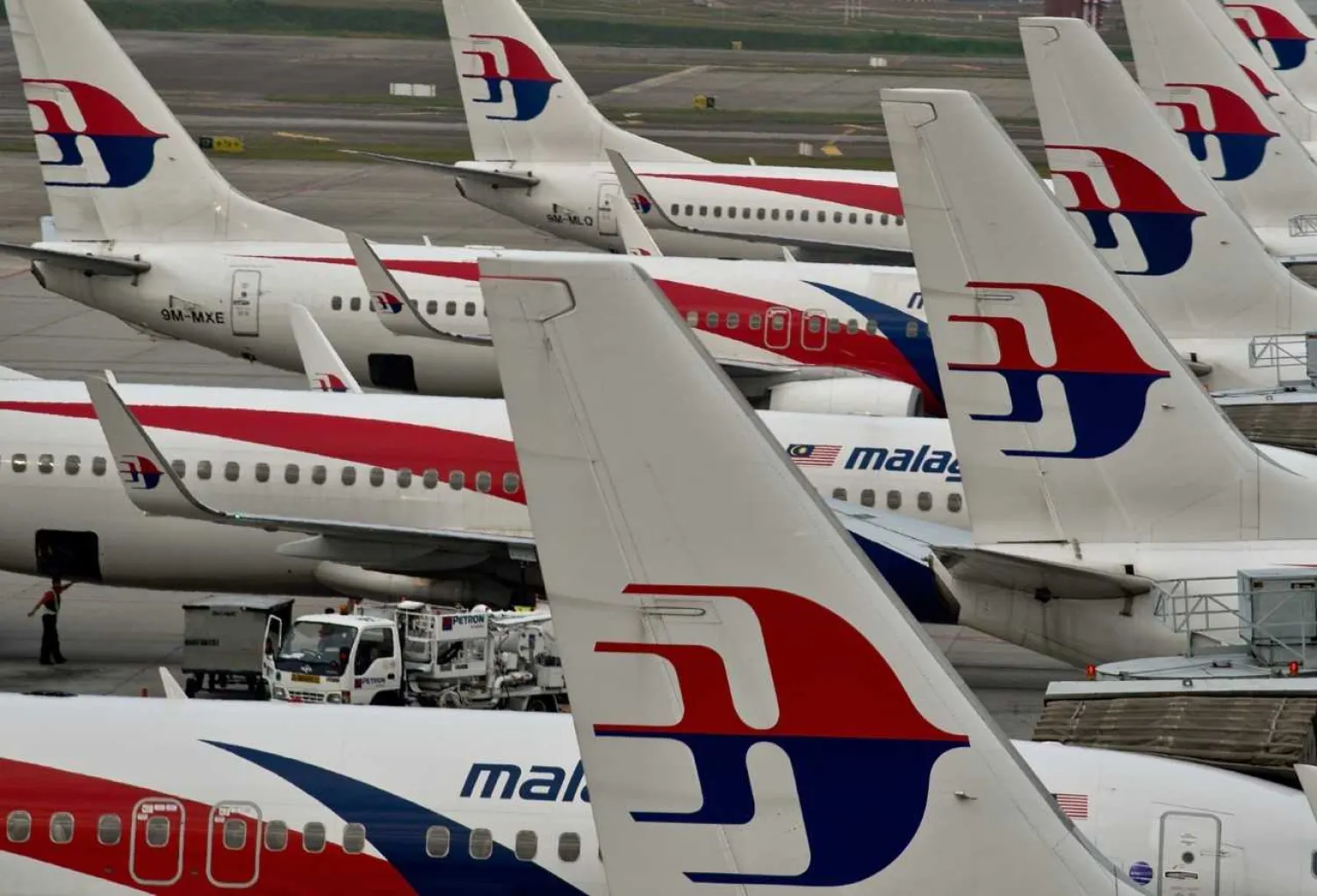 Airport ground staff walk past Malaysia Airlines planes parked on the tarmac at the Kuala Lumpur International Airport in Sepang on June 17, 2014. MANAN VATSYAYANA—AFP