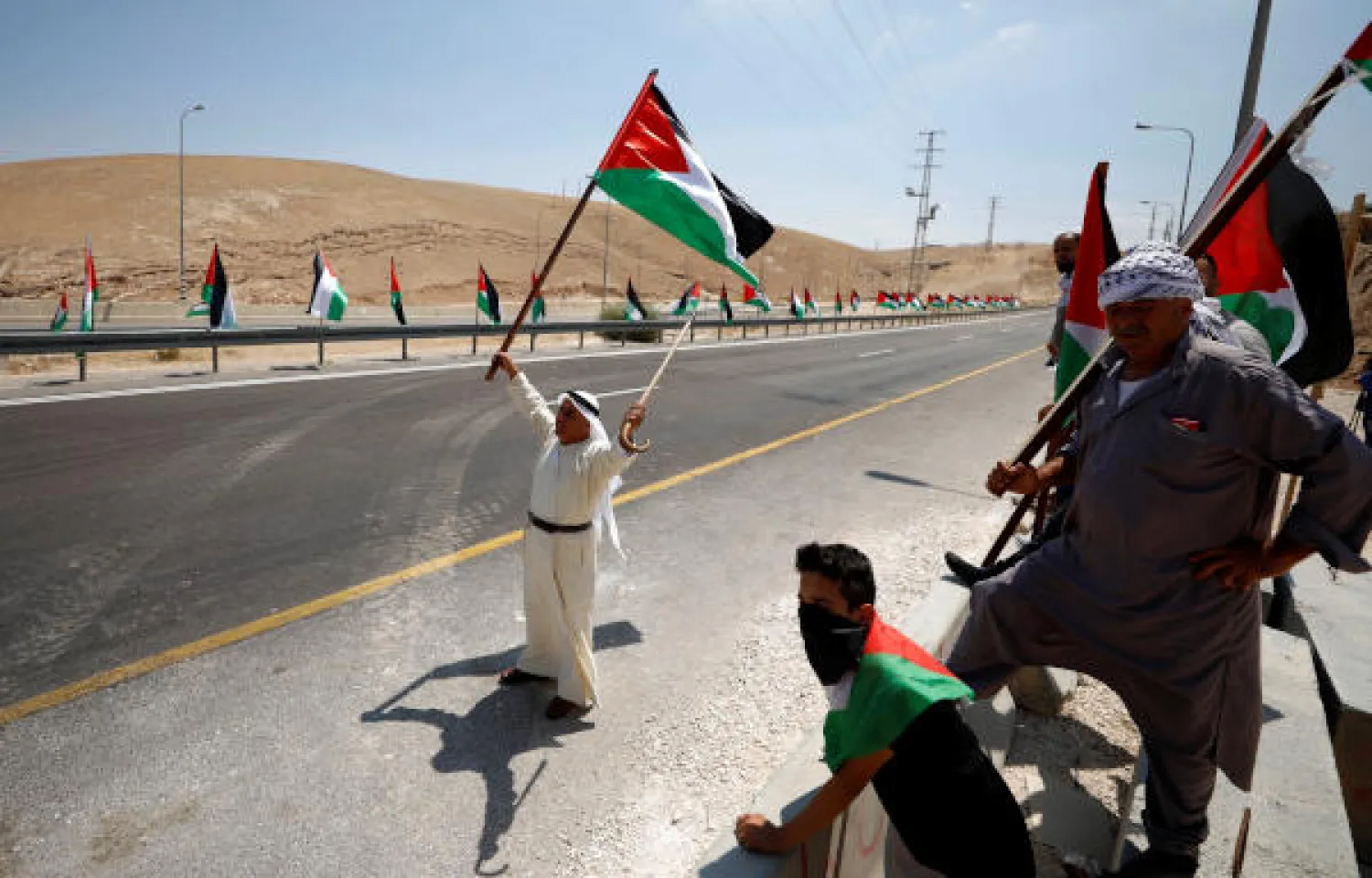 A demonstrator holds a Palestinian flag during a rally in support of Khan al-Ahmar residents in the Bedouin village of Khan al-Ahmar, in the occupied West Bank August 1, 2018. REUTERS/Mohamad Torokman