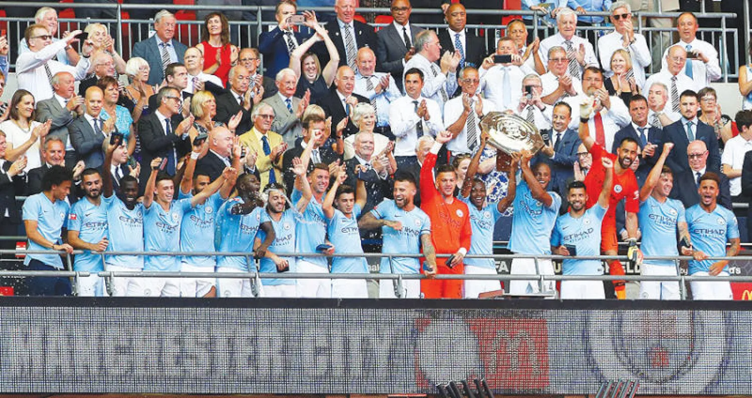 لاعبو مانشستر سيتي على منصة التتويج في ويمبلي يحتفلون بالدرع الخيرية (رويترز)