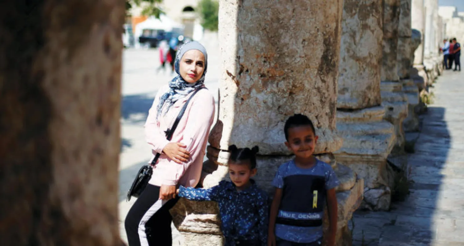 آلاء مسالمة نازحة سورية إلى الأردن في زيارة لموقع روماني أثري قرب العاصمة بصحبة ولديها (رويترز)