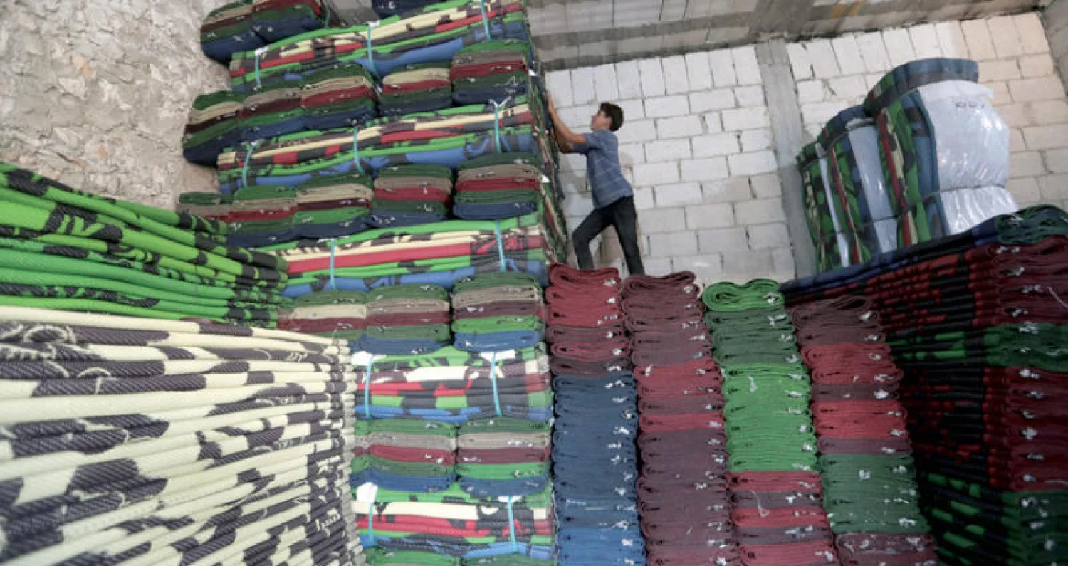 طفل يجلس على سجاد محلي يحاك في محافظة إدلب (رويترز)