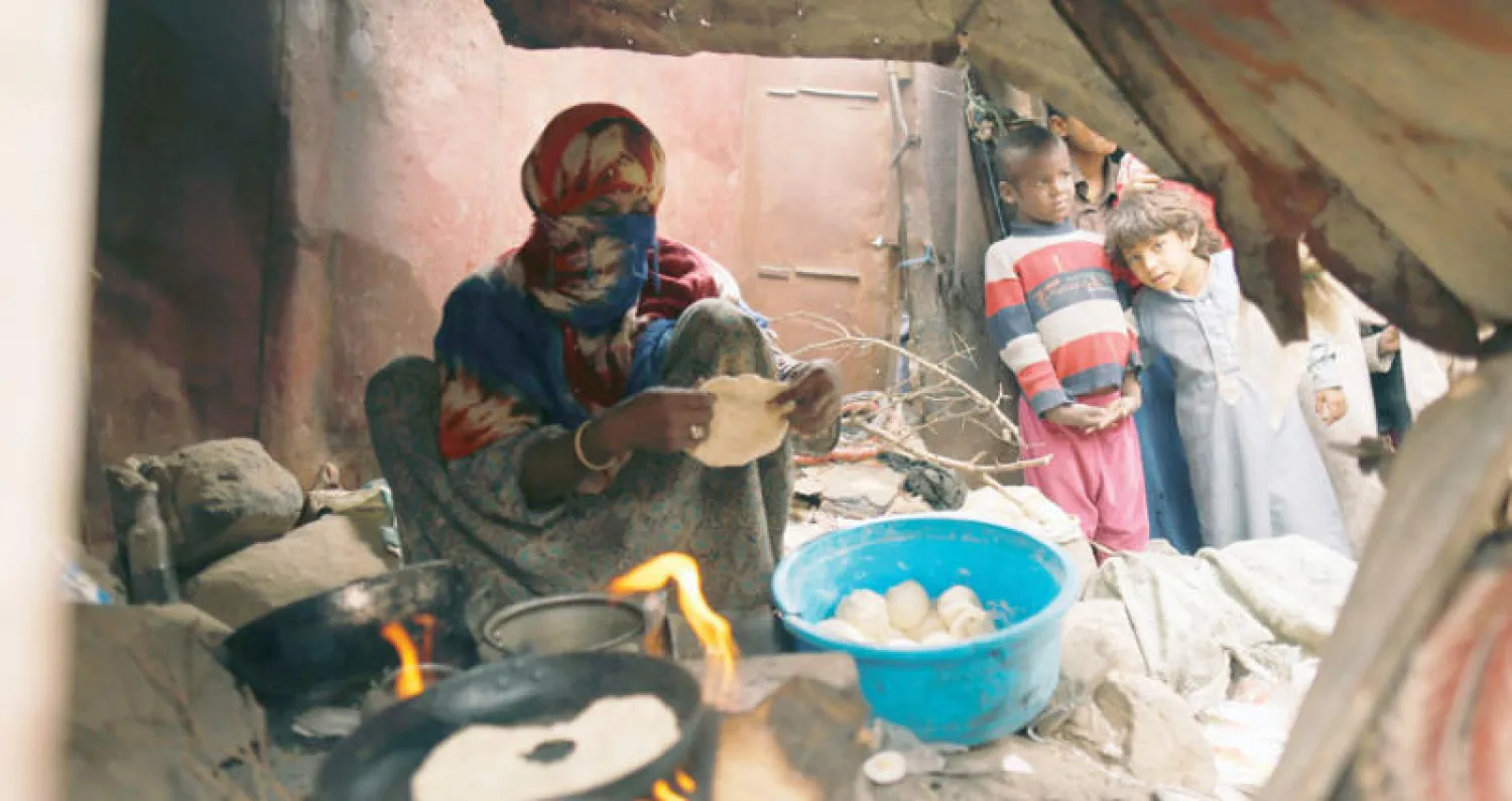 أطفال يراقبون امرأة تصنع الخبز لنازحين من الحديدة في صنعاء (رويترز)