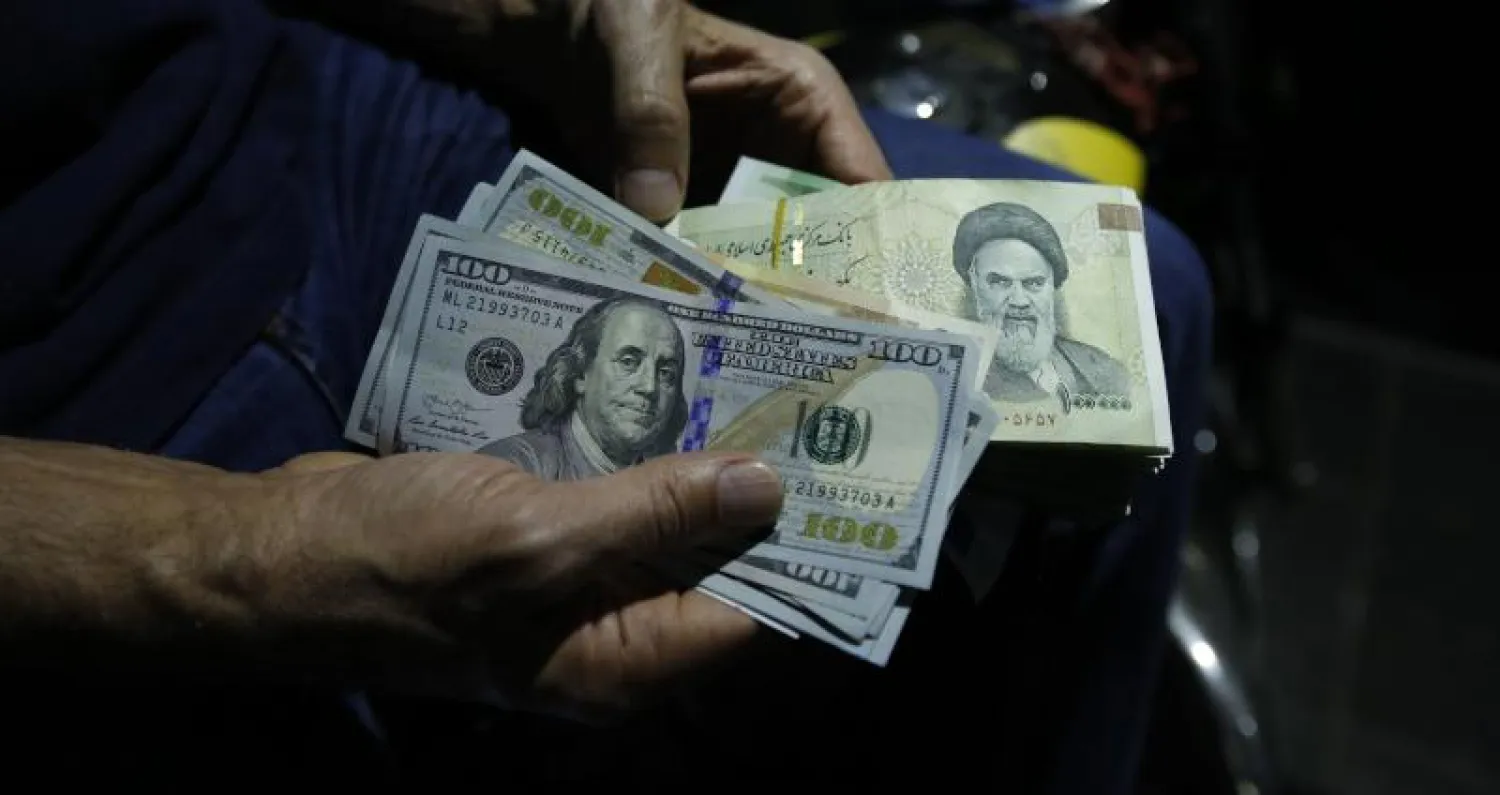 رجل يبادل ريالات إيرانية بدولارات أميركية بمحل صرافة في طهران (أ.ف.ب)