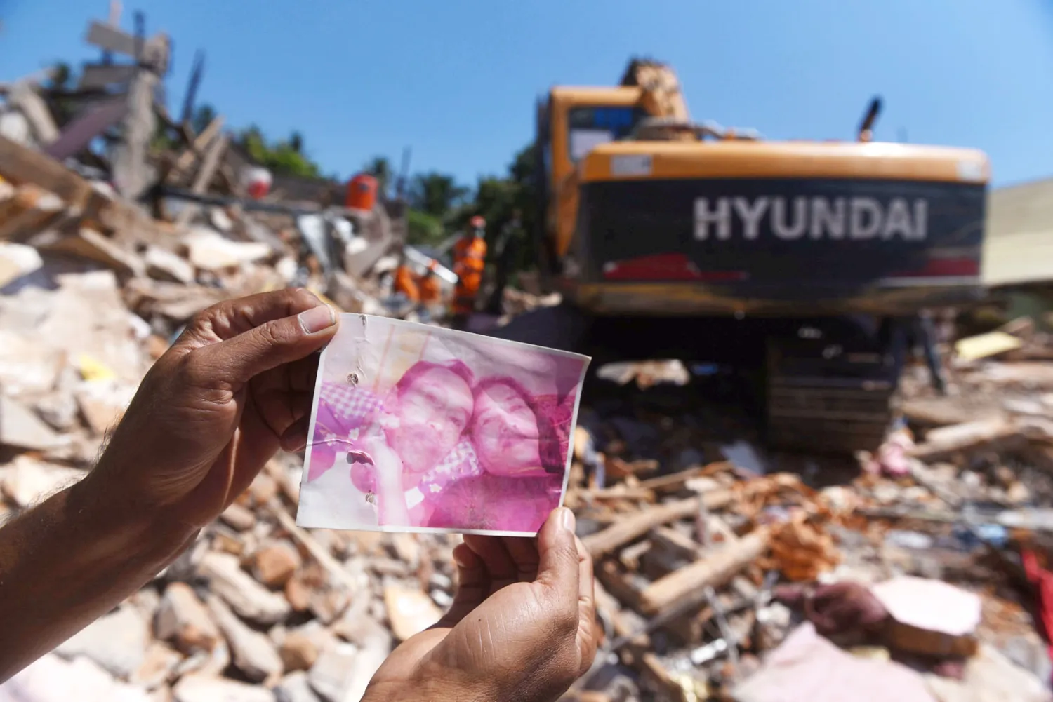 أحد الناجين يعرض صور بعض ضحايا الزلزال من أقاربه