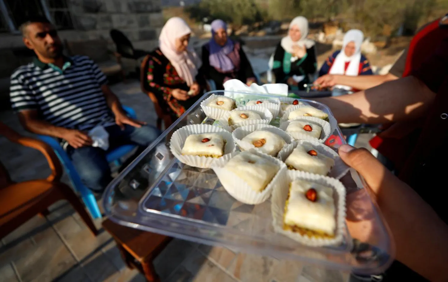 Relatives of Rashida Tlaib distribute sweets as they celebrate her election victory, in the village of Beit Our al-Fauqa in the Israeli-occupied West Bank. (Reuters)