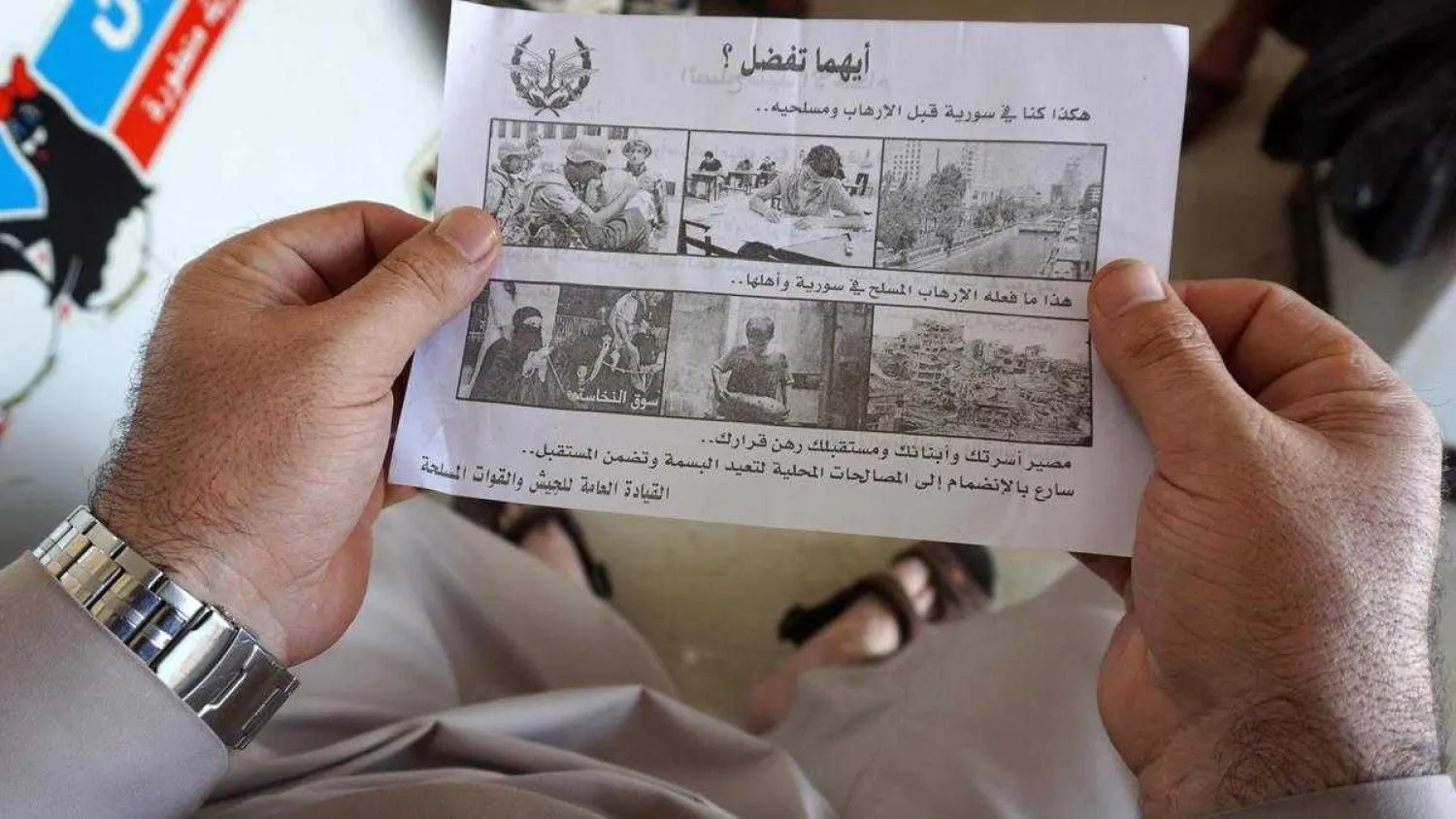 A man holds a leaflet dropped by helicopters over the Syrian city of Saraqib on August 9, 2018. AFP